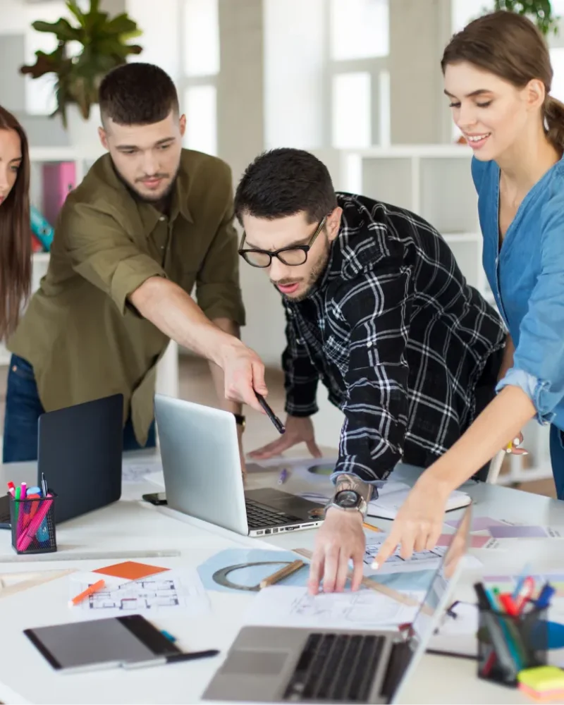 young-creative-people-with-laptop-sketches-discussing-new-project-together-group-guys-gals-working-modern-cozy-office 1